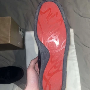 Mörk blåa Louboutin byte sökes!!! - Säljer ett par eleganta mörk blåa sneakers från Christian Louboutin i mocka. Skorna har den ikoniska röda sulan och snörning framtill. Perfekta för den som vill ha en stilren look med en touch av lyx.