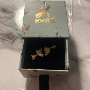 Guldfärgad ring med pil och hjärta - Snygg guldfärgad ring från Ioaku med ett unikt designat hjärta delat av en pil. Man kan töja ut eller in ringen lite så den passar.