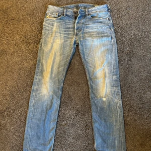 Diesel jeans - Säljer ett par snygga blå jeans från Diesel med en regular slimfit passform. Riktigt sköna slitningar, perfekt till sommar och vår!
