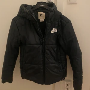 Svart dunjacka från Nike - Säljer en svart dunjacka från Nike. Bra höst o vår jacka! Passar XXS-S