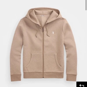 Beige hoodie från Ralph Lauren - Säljer en stilren beige hoodie från Ralph Lauren med dragkedja och klassisk logga på bröstet. Tröjan har långa ärmar och en praktisk huva med snörning. Perfekt för en avslappnad look. Tillägg -  helt ny! Kan mötas upp, kan även fraktas.