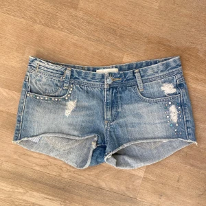 Jeansshorts  - Snygga blåa lågmidjade jeansshorts. De är i bra skick förutom att de har tappat några diamanter från jeans knappen. Många snygga detaljer, men säljer då de är för stora för mig. Midjemåttet är 39 cm tvärs över 💕