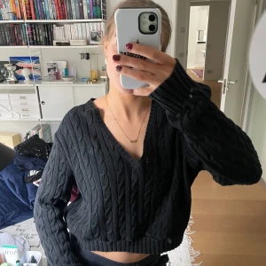 Svart stickad tröja - Säljer en svart stickad tröja från Ralph Lauren Sport. Tröjan har en v-ringad design och långa ärmar, perfekt för kyligare dagar. Den är croppad och ger en trendig look. Passar bra till både jeans och kjol. Strorlek är XL men jag använde oversized😇
