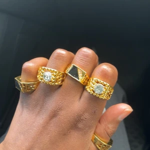 5 st Guldfärgade ringar med stenar - Säljer ett set av guldfärgade ringar med stora dekorativa stenar. Ringarna har olika design med både klara och svarta stenar, vilket ger en lyxig känsla. Perfekt för att ge en extra touch till din stil.