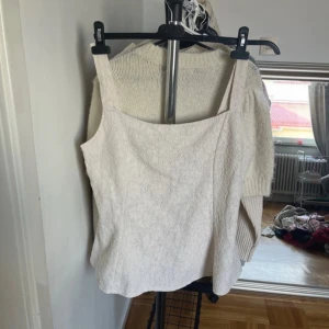 Vit spetslinne - Säljer ett stilrent vitt spetslinne med breda axelband. Perfekt för en somrig look eller att bära under en kavaj. Linnet har en elegant och feminin design.