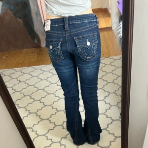 True religion jeans - Säljer ett par mörkblå jeans från True Religion med låg midja och bootcut-stil. Byxorna är i modellen joey och i storlek 27. Köpta på vinted, de har en liten defekt på sista bilden men inget som märks❤️