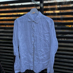 Vit linneskjorta från Massimo Dutti - Säljer en stilren vit skjorta i 100% linne från Massimo Dutti. Skjortan har långa ärmar och knappar framtill. Perfekt för en avslappnad men ändå elegant look.