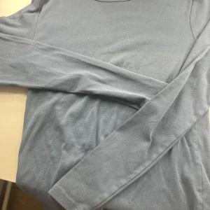 Ljusblå långärmad tröja från 157 - Säljer en enkel och stilren ljusblå långärmad tröja från 157 i storlek XS. Tröjan har rund halsringning och är gjord i mjukt bomullsmaterial. Perfekt basplagg att ha i garderoben!