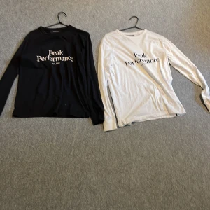 Svart och vit långärmad tröja från Peak Performance - Två långärmade tröjor från Peak Performance, en svart och en vit, båda med logga tryckt framtill. Klassisk rund halsringning och normal passform. Perfekta för en stilren och enkel look. Om man köper båda får man det billigare pris kan diskuteras. 125 st 