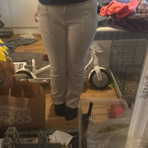 Grå mjukisbyxor från Juicy Couture - Säljer ett par grå mjukisbyxor från Juicy Couture i storlek M. Byxorna har raka ben, dragsko i midjan och fickor både fram och bak med lock och knappdetaljer bak. Mjukt material som känns skönt mot huden.