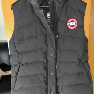 Svart dunväst från Canada Goose - Säljer en svart dunväst från Canada Goose, storlek L. jag har haft den i typ 5 år men den har bara varit upphängd i garderoben, den har använts Max 2-3 gånger så den är som ny.
