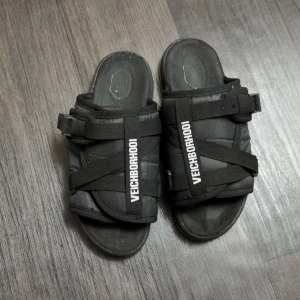 Svarta sandaler från VECHORNHOOD - Svarta sandaler med breda remmar och justerbara spännen. Öppen tå och platt sula, perfekt för varma dagar. Märkeslogga på ovansidan av remmarna ger en cool streetkänsla.