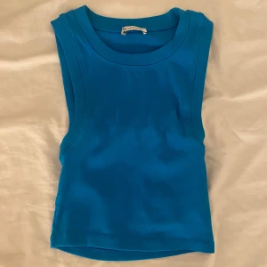 Blå ribbad linnetopp från Zara - Säljer en blå ribbad linnetopp från Zara. Toppen är ärmlös med rund halsringning och har en tight passform. Perfekt för sommaren och enkel att matcha med olika outfits.
