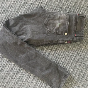 Svarta Tramarossa jeans med röda detaljer - Säljer ett par svarta tramarossa jeans med snygga röda sömmar och detaljer. Jeansen har raka ben, klassiska bakfickor och silverfärgade knappar. Märkeslapp bak i midjan och coolt innerfoder med mönster. Nypris är 5500 kr och skicket är bra finns en liten fläck på fickan, se första bilden! Skriv vid funderingar!