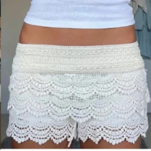 Spets shorts - Superfina vita shorts med bred resår i midjan och flera lager volang i spets. Perfekta för sommaren och ger en romantisk vibe till outfiten. Snygga att matcha med en enkel topp eller linne.