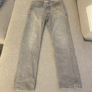 Grå jeans, Jack & Jones 31/32 - Snygga grå jeans från Jack & Jones med klassisk femficksdesign och raka ben. Jeansen har bälteshällor, knapp och dragkedja i gylfen. Perfekta för en avslappnad stil. 32 i bredd och 31 i längd.
