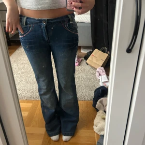Blå bootcut jeans med broderi - Säljer ett par blå bootcut jeans med färgglada broderade detaljer vid fickorna och bakfickorna. Jeansen är lowwaist❤️
