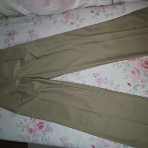 Beiga vida kostymbyxor i bomull - Snygga beiga kostymbyxor i rak och vid modell. Byxorna har klassisk passform och är tillverkade i mjuk bomull, perfekta för en clean och stilren look. Passar dig som gillar minimalistisk stil och vill ha något som funkar till många outfits.