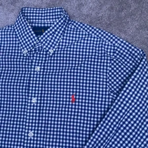 Blårutig skjorta från Ralph Lauren - FRAKT 1-3 DAGAR INOM POSTNORD Säljer denna blårutiga stiliga skjortan i ralph laurenpassar perfekt till s i storlek kan passa m också inget som helst fel med skjortan den är i nyskick och PRISET ÄR EJ HUGGET I STEN!! 