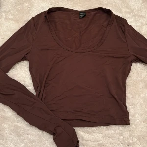 Brun långärmad topp från SHEIN - Säljer en brun långärmad topp från SHEIN i storlek XS. Toppen har en rundad, djup urringning och är croppad i modellen. 