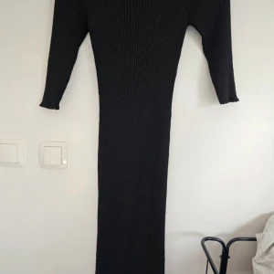 Svart ribbad långklänning från Lindex - Säljer en svart ribbad långklänning från Lindex med rund hals och långa ärmar. Klänningen är stickad i en blandning av viskos och metallfiber, vilket ger en snygg glansig finish. Perfekt för dig som gillar en stilren och bekväm look med lite edge.