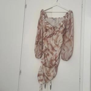 Klänning med chiffong  - En perfekt sommarklänning med snören både vid bysten och nere vid sidan som man kan reglera. Det finns även en liten dragkedja på vänster sida vid revbenshöjd. Inte så stretchigt material. Har inte använt den även om prislappen är borttagen. 