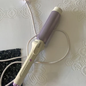 Ljuslila locktång från OBH Nordica - Snygg locktång i ljuslila och vitt med justerbar värme upp till 200°C och jonfunktion. Ergonomiskt handtag med lila powerknapp och lång sladd. Perfekt för att fixa mjuka lockar eller beach waves hemma.