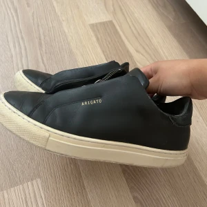 Svarta sneakers från Axel Arigato, strl 37/38 - Svarta sneakers från Axel Arigato i skinn i strl 37, funkar alldeles utmärkt 38 också. Har en del slitage men skorna fungerar utmärkt. 💕💕