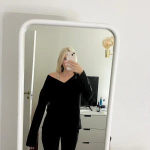 Svart stickad offshoulder-tröja - Säljer en svart stickad tröja med offshoulder-design och långa ärmar. Tröjan har en avslappnad passform och är perfekt för dig som gillar en enkel men snygg stil. Passar till både jeans och kjol för en chill look.