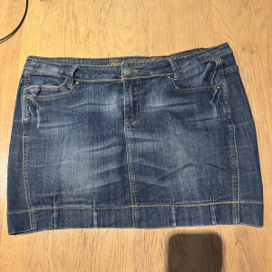 Jeanskjol från Broadway, kort modell - Snygg kort jeanskjol från Broadway med slitningar och kontrastsömmar. Kjolen har knapp och dragkedja framtill samt bälteshällor. 