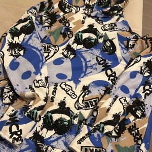 Färgglad hoodie med graffiti från Lindex - Säljer en hoodie från Lindex i storlek 158/164 med coolt graffitiinspirerat tryck i blått, svart, beige och grönt. Tröjan har luva och lång ärm. Materialet är mjukt och skönt.