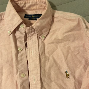 Ralph lauren skjorta - Riktigt snygg ljusrosa Ralph lauren skjorta som är i toppskick, kameran visar inte riktigt rätt färg därav dåliga bilder. Strl S, slimfit