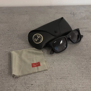 Svarta Ray-Ban Justin solglasögon - Säljer ett par stilrena Ray-Ban Justin RB4165 solglasögon i matt svart med mörka glas. Klassisk fyrkantig form och Ray-Ban-logga på linsen. Kommer med originalfodral och putsduk. Perfekta för dig som vill ha en tidlös och cool look.