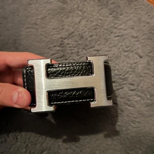 Snyggt svart bälte med ett H märke - Snyggt bälte 