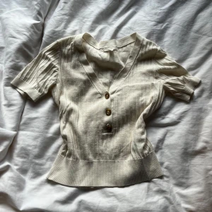 Vintage topp - Superfin ribbad topp från H&M i lite krämvit/beige färg med v-ringning och tre snygga knappar framtill. Så snygg nu till hösten!💗