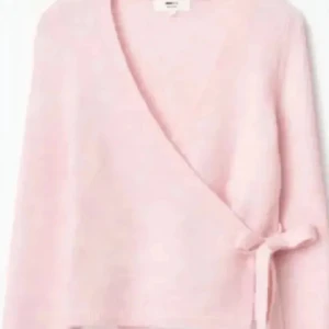 Ljusrosa omlottkofta med knytband - Superfin ljusrosa omlottkofta med knytband i sidan. Koftan har lång ärm och en mjuk, stickad känsla som gör den perfekt för lager på lager. Enkel och stilren design som passar till många olika outfits.Från Gina Tricot. Bara provad