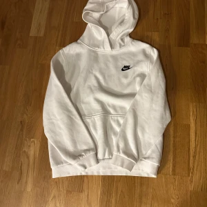 Vit hoodie från Nike XL - Säljer en clean vit hoodie från Nike i storlek XL. Klassisk design med svart Nike-logga på bröstet, stor huva och magficka. Mjuk och skön bomullsmix, perfekt för chill eller streetwear. Långärmad med ribbade muddar och avslappnad passform.