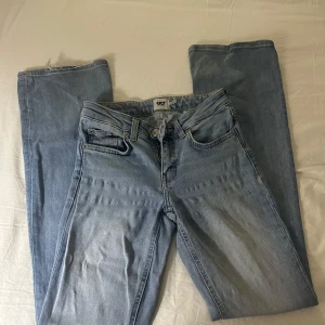 Ljusblå lågmidjade bootcut jeans - Snygga lågmidjade ljusblåa jeans med bootcut-ben. Modellen är lågmidjad och har en cool vintage-vibe med slitningar och ljus tvätt. Perfekta för dig som gillar avslappnad stil och vill ha jeans som sticker ut lite extra.