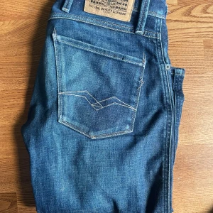 Replay Anbass - Säljer ett par klassiska blå jeans från Replay med snygga kontrastsömmar och femficksdesign. Byxorna har normal passform och är tillverkade i slitstarkt denim. Perfekta för dig som gillar stilrena och tidlösa jeans.