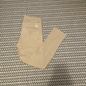 Beiga chinos från WINWIN - Snygga beiga chinos från WINWIN med klassisk passform och diskret bakficka. Perfekta för en clean och stilren look. Byxorna har en liten vit logga vid bakfickan och är gjorda i ett mjukt bomullsmaterial.