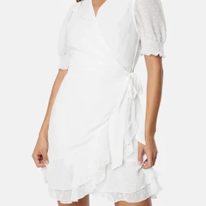 Vit omlottklänning med volang - Söt vit omlottklänning med kort puffärm och smockdetalj vid ärmslut. Klänningen har volangkant nertill och knyts i midjan. original pris 599