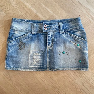 Cool jeanskjol  - Säljer en blå jeanskjol med coola slitningar och nitar i silver och turkos framtill❤️‍🔥aldrig använd! Midjemått: 41cm