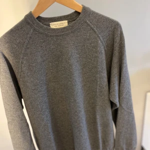 Grå tröja i ull och kashmir från Filippo De Laurentiis - Mjuk och stilren grå tröja från Filippo De Laurentiis, tillverkad i en exklusiv blandning av ull och kashmir. Tröjan har rund halsringning och långa ärmar, perfekt för en klassisk och avslappnad look. Nypris - 2599kr