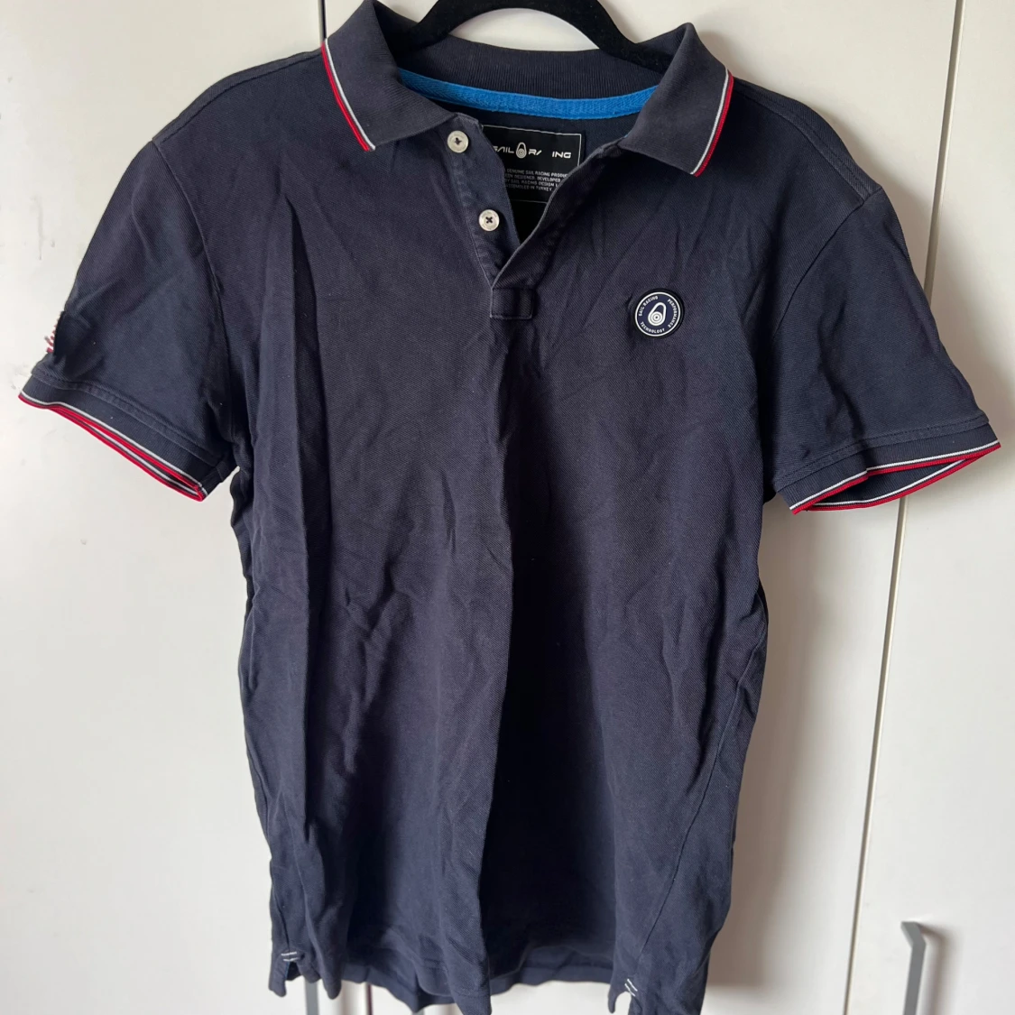 Mörkblå pikétröja med röd och vit kant