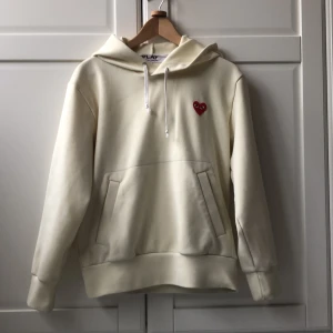 Vit hoodie från Comme des Garçons Play - Säljer en stilren vit hoodie från Comme des Garçons Play med det ikoniska röda hjärtat broderat på bröstet. Jag köpte den va en kompis som köpte den från deras hemsida för cirka 3000, mitt pris 900 vilket är väldigt bra för skicket den är i. Den är lite nopprig men de går att få bort och den är inte ny tvättad så den kan se lite smutsig ut. Skriv för minsta fundering! Fler bilder får du privat