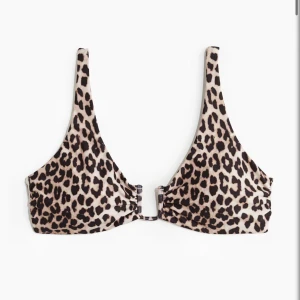 Leopardmönstrad bikiniöverdel med knyt - Säljer en snygg bikiniöverdel med leopardmönster. Modellen har smala axelband och knyt i ryggen för justerbar passform. Perfekt för sommardagar på stranden eller vid poolen. Materialet känns mjukt och följsamt. Säljs då den var förstor för mig. Där av knappt använd❤️ (pris kan diskuteras)