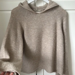 Beige stickad hoodie från Gina Tricot - Mysig beige stickad hoodie från Gina Tricot. Tröjan har långa ärmar, huva och en något croppad passform. Använd få gånger, därav i fint skick. Ytterst lite nopprig. 🙌🏼 Är inte omöjligt att få ner priset något! 