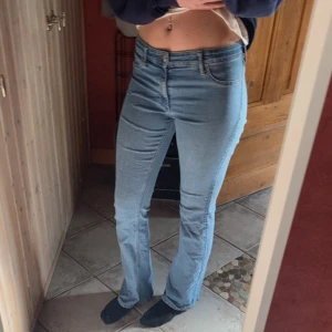 Ljusblå bootcut jeans - Säljer ett par ljusblå jeans med bootcut passform och klassisk femficksdesign. Jeansen har normal passning och är lågmidjade, perfekta för en avslappnad och trendig look. Stängs med dragkedja och knapp framtill.