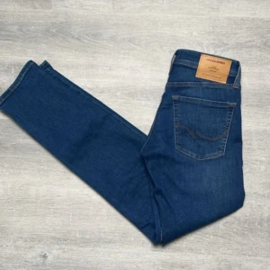 Blå jeans från Jack & Jones - Snygga blå jeans från Jack & Jones med klassisk femficksdesign och bruna sömmar. Jeansen har en rak passform och är tillverkade i ett slitstarkt denimtyg. Perfekta för en stilren vardagslook.