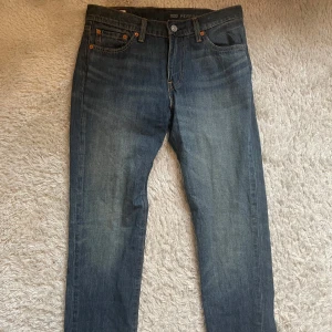 Levi's 511 blå jeans W30 L32 - Säljer ett par klassiska blå Levi's 511 jeans med normal passform och raka ben. Jeansen har fem fickor, knappgylf och den ikoniska läderpatchen bak i midjan. Perfekta till vardags för en stilren look.